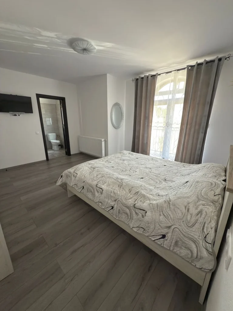 Pat matrimonial și ieșire către balcon în dormitorul cabanei