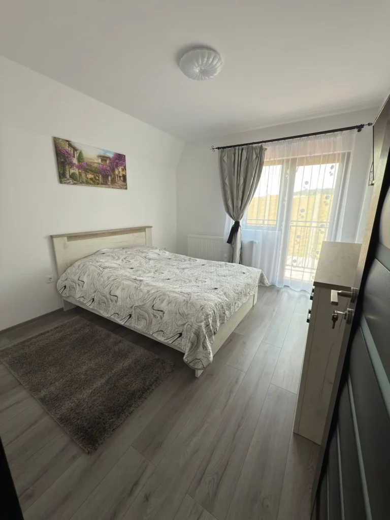 Dormitor luminos cu pat matrimonial și acces către balcon