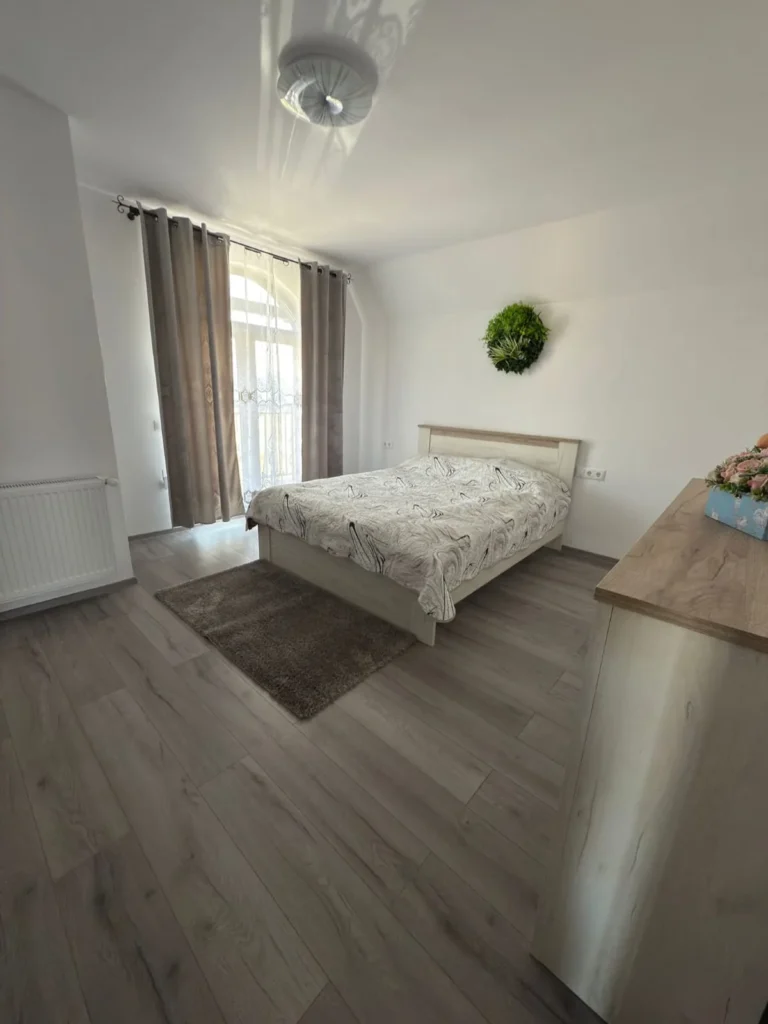 Dormitor matrimonial cu mobilier din lemn și fereastră largă