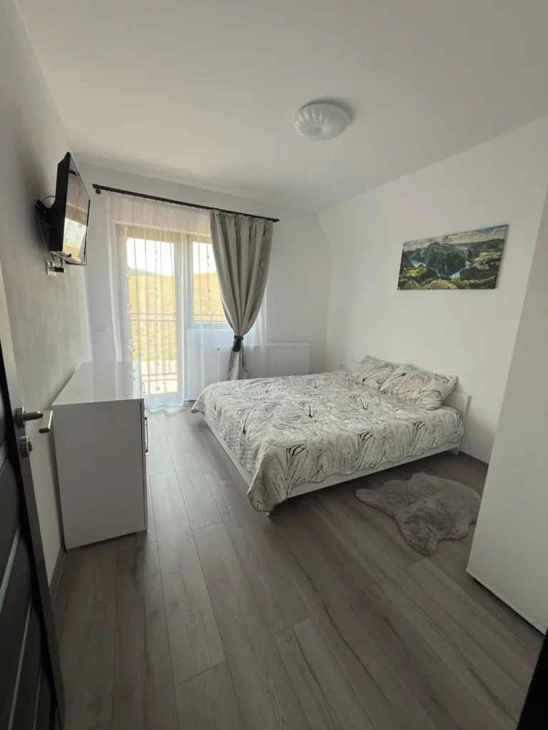 Dormitor cu pat dublu și ușă vitrată spre exterior